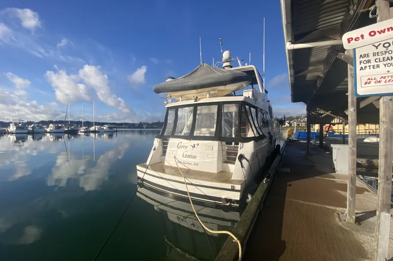 Slide: The Image of Compass 55 boat docked at marina, clear sky, calm water reflections. - 122