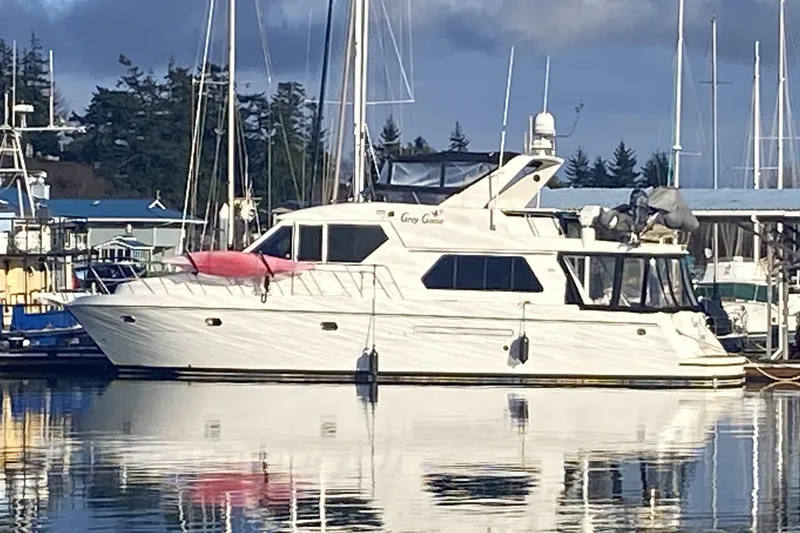 Slide: The Image of Compass 55 yacht from 2000 docked at a marina, reflecting on calm water. - 2