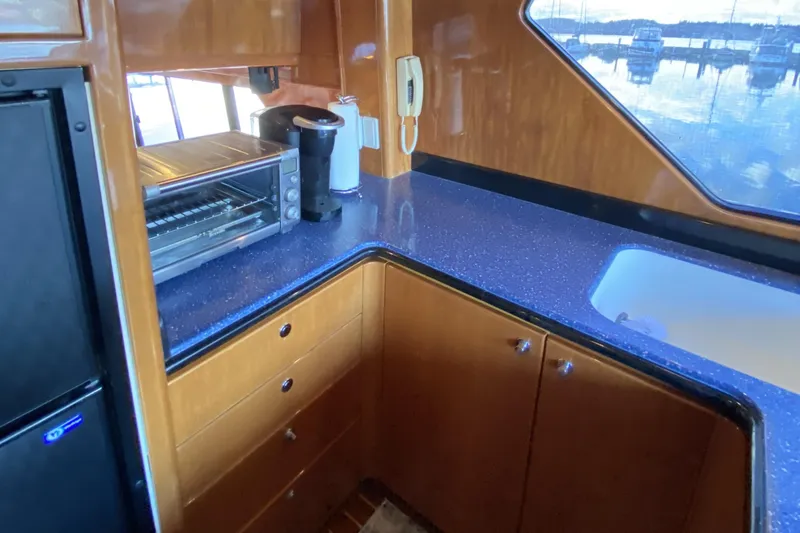 Slide: The Image of Compact kitchen area in a 2000 Compass 55 yacht with appliances and wooden cabinetry. - 27