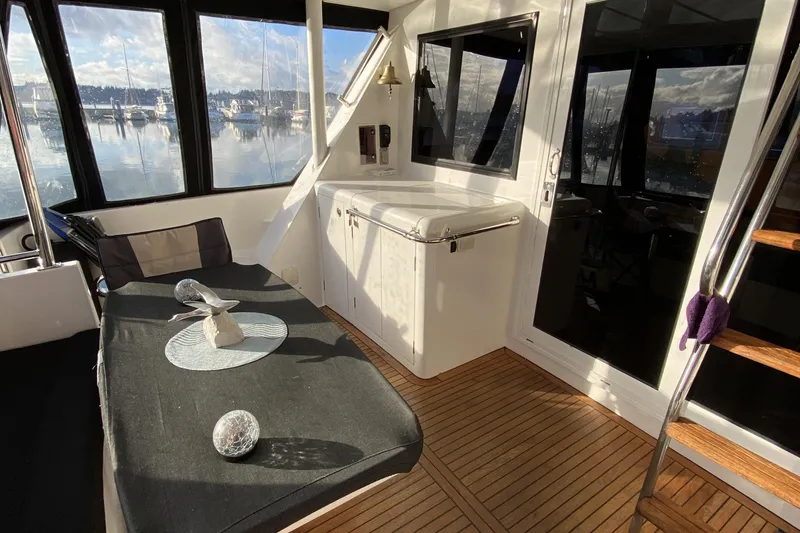 Slide: The Image of Interior of 2000 Compass 55 yacht with seating, table, and scenic marina view. - 5