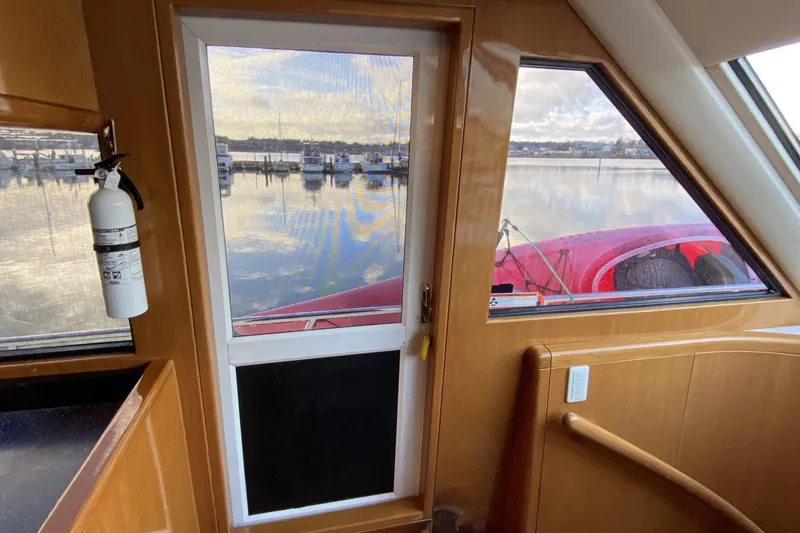 Slide: The Image of Interior view of Compass 55 yacht, showcasing wooden finish and marina through windows. - 52