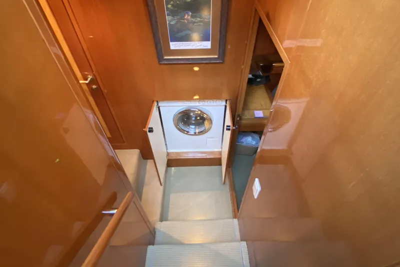 Slide: The Image of Laundry area inside a 2000 Compass 55 yacht, featuring wooden cabinetry and a washing machine. - 54