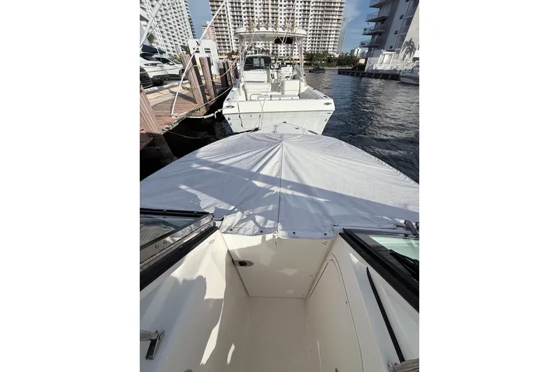 Slide: The Image of 2022 Pursuit DC 266 Dual Console boat docked at marina, covered bow, cityscape background. - 11