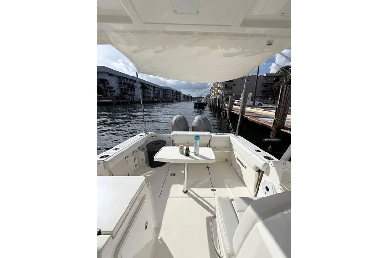 Slide: The Image of 2022 Pursuit DC 266 Dual Console boat interior with table, docked by waterfront buildings. - 12