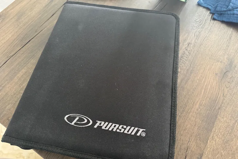 Slide: The Image of Black Pursuit folder on wooden table, related to 2022 DC 266 Dual Console. - 16