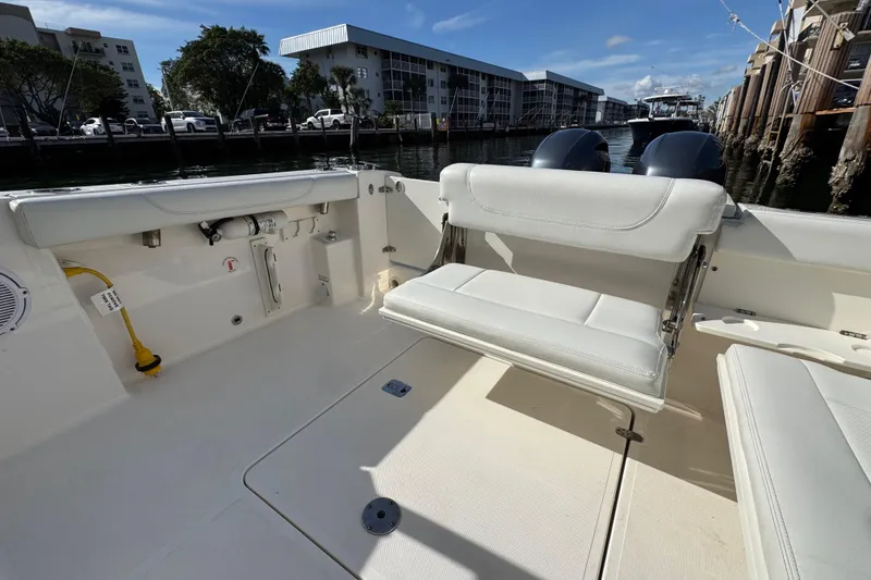 Slide: The Image of 2022 Pursuit DC 266 Dual Console boat interior with seating and dockside view. - 32