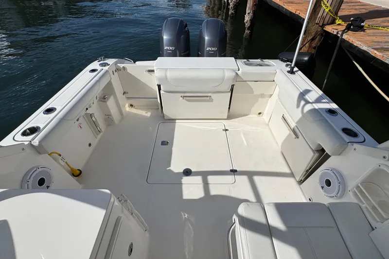 Slide: The Image of 2022 Pursuit DC 266 Dual Console boat interior with twin engines, docked by wooden pier. - 36