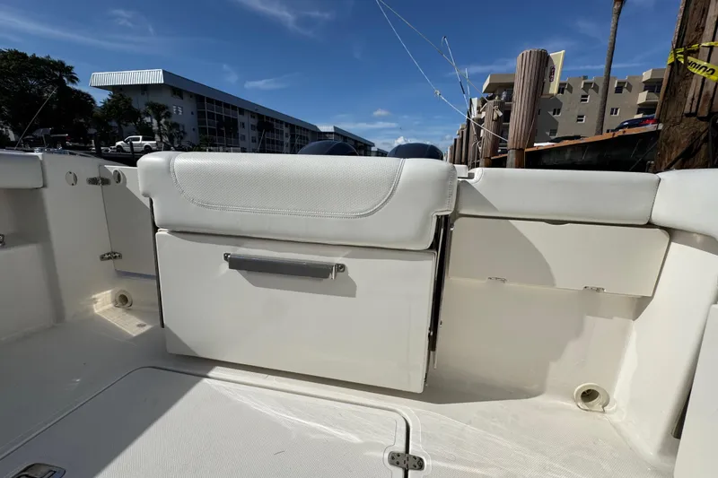 Slide: The Image of 2022 Pursuit DC 266 Dual Console boat interior with seating and storage, docked under clear skies. - 37