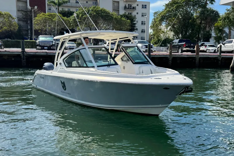 Slide: The Image of 2022 Pursuit DC 266 Dual Console boat on water near dock, surrounded by trees and buildings. - 4