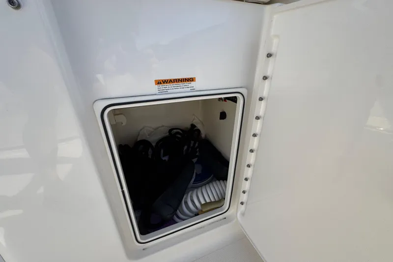 Slide: The Image of Storage compartment on 2022 Pursuit DC 266 Dual Console boat, containing coiled hose and gear. - 44