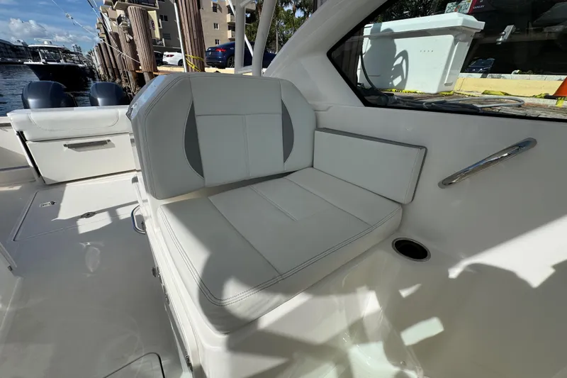 Slide: The Image of 2022 Pursuit DC 266 Dual Console boat interior with white seating and docked view. - 55