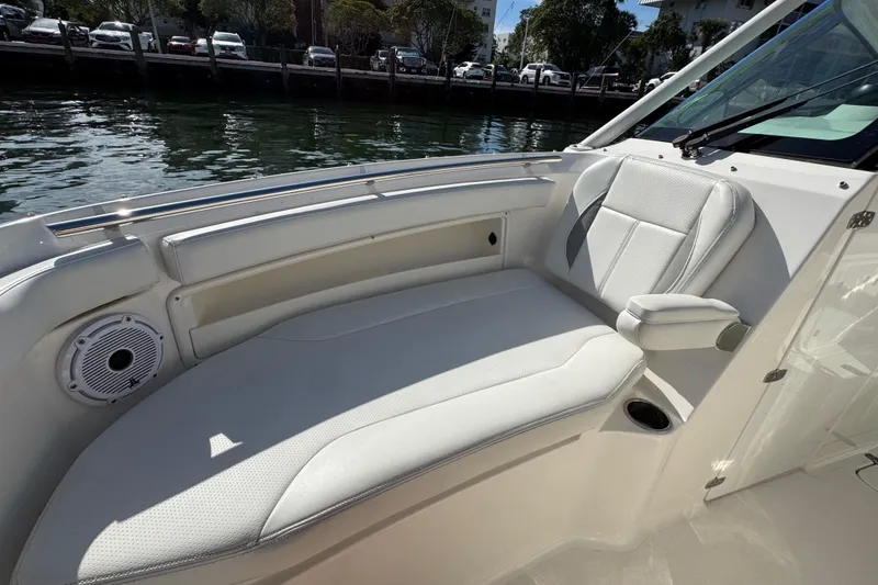 Slide: The Image of 2022 Pursuit DC 266 Dual Console boat interior with white seating and waterfront view. - 77