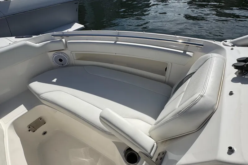 Slide: The Image of 2022 Pursuit DC 266 Dual Console boat with white seating and speaker, docked by water. - 79