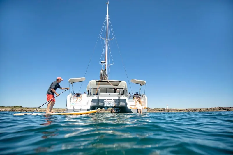 Slide: The Image of Man paddleboarding near 2026 Excess 11 catamaran on a sunny day. - 29