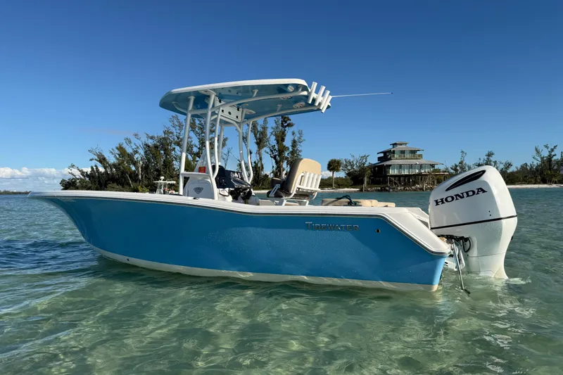 Slide: The Image of 2019 Tidewater 220 LXF boat with Honda engine in clear water, near a coastal house. - 11
