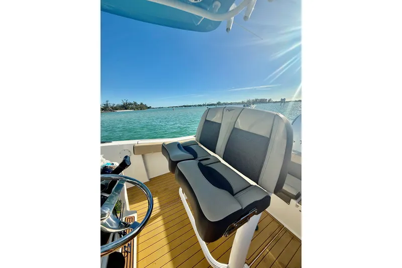 Slide: The Image of 2019 Tidewater 220 LXF boat interior with dual seats, steering wheel, and scenic water view. - 5