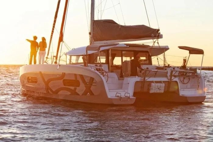 Slide: The Image of Manufacturer Provided Image: 2026 Excess 11 catamaran sailing at sunset with people on deck. - 14