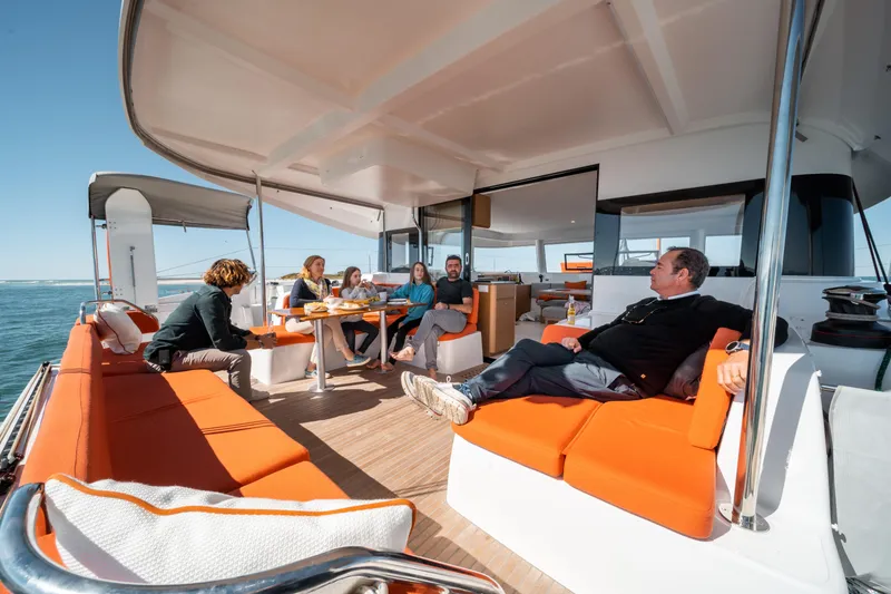 Slide: The Image of People relaxing on the deck of a 2026 Excess 14 catamaran, enjoying the ocean view. - 15