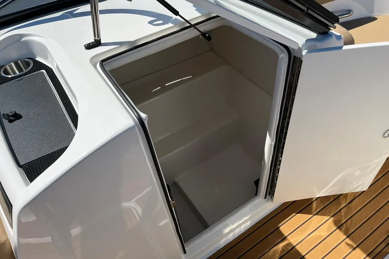 Slide: The Image of 2026 Bayliner VR6 Bowrider OB interior storage compartment with open door on wooden deck. - 12