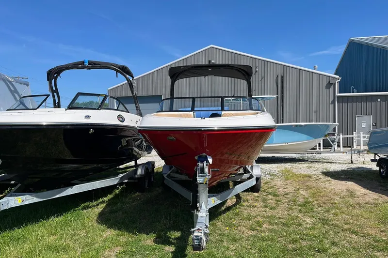 Slide: The Image of 2026 Bayliner VR6 Bowrider OB on trailer, parked outdoors near metal buildings. - 4