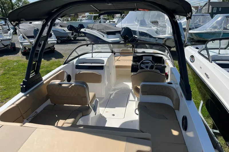 Slide: The Image of 2026 Bayliner VR6 Bowrider OB interior with seating and steering wheel, parked among other boats. - 8