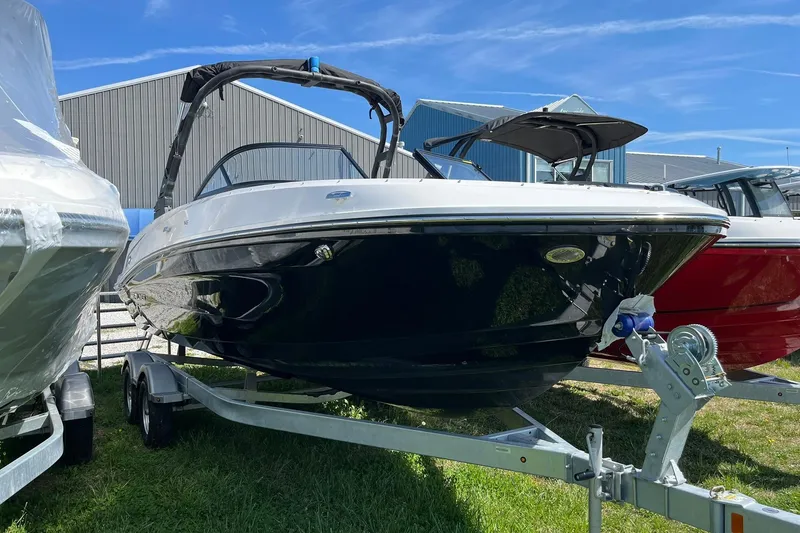 Slide: The Image of 2026 Bayliner VR6 Bowrider OB on trailer, parked outdoors near other boats. - 3
