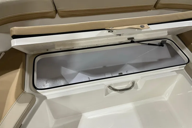 Slide: The Image of 2026 Bayliner Trophy T22SC boat storage compartment with beige seating and stainless steel handle. - 14