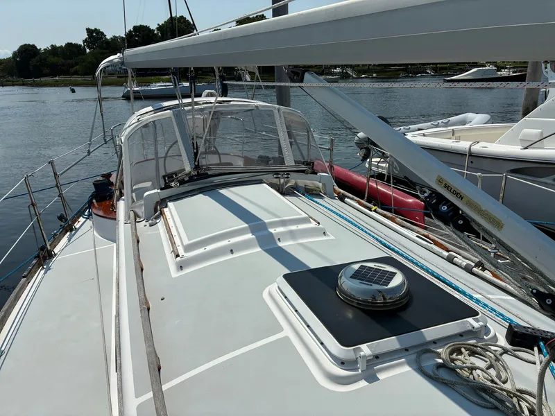 Slide: The Image of The image shows the deck of a 2001 Cape Dory Robinhood 36. It is docked, surrounded by other boats. The deck is clean and well-maintained, with a clear view of the rigging and cockpit. - 14