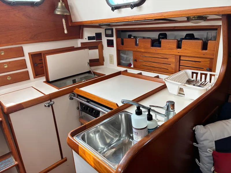 Slide: The Image of The galley of a 2001 Cape Dory Robinhood 36 with wooden cabinets and a stainless steel sink. - 43