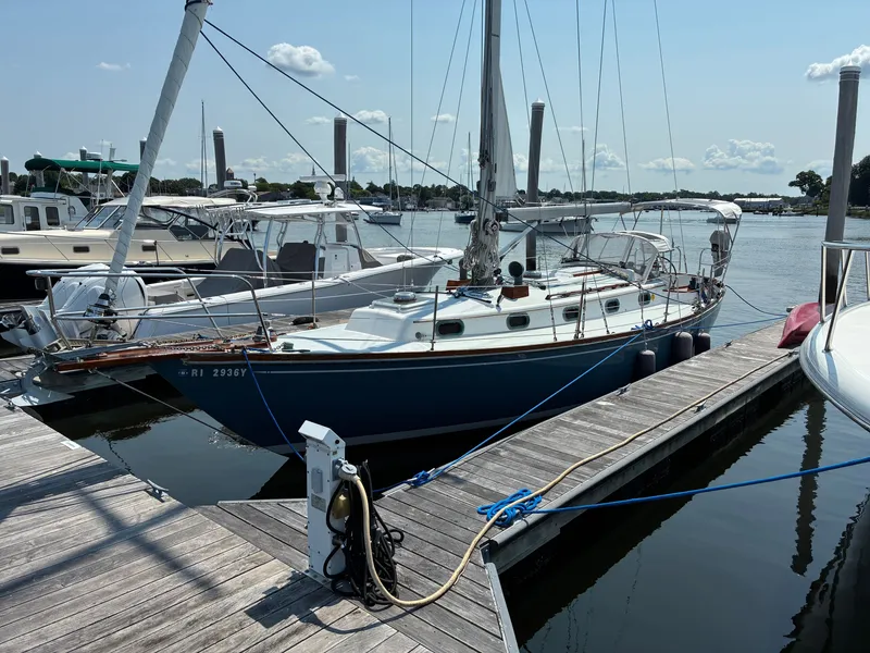 The Image of A 2001 Cape Dory Robinhood 36 is docked. It has a blue hull and is surrounded by other boats. - 0