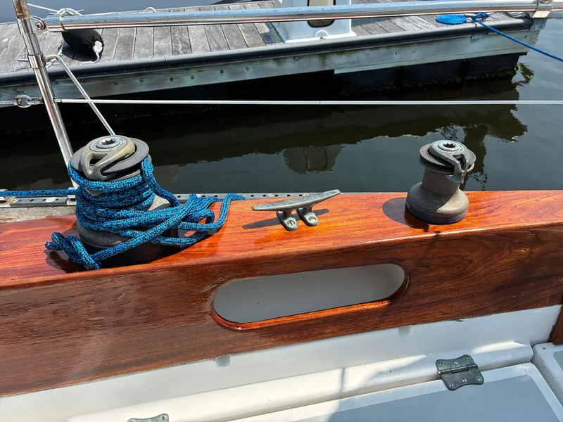 Slide: The Image of The image shows the deck of a 2001 Cape Dory Robinhood 36. There's a winch with blue rope and a cleat on polished wood. - 32