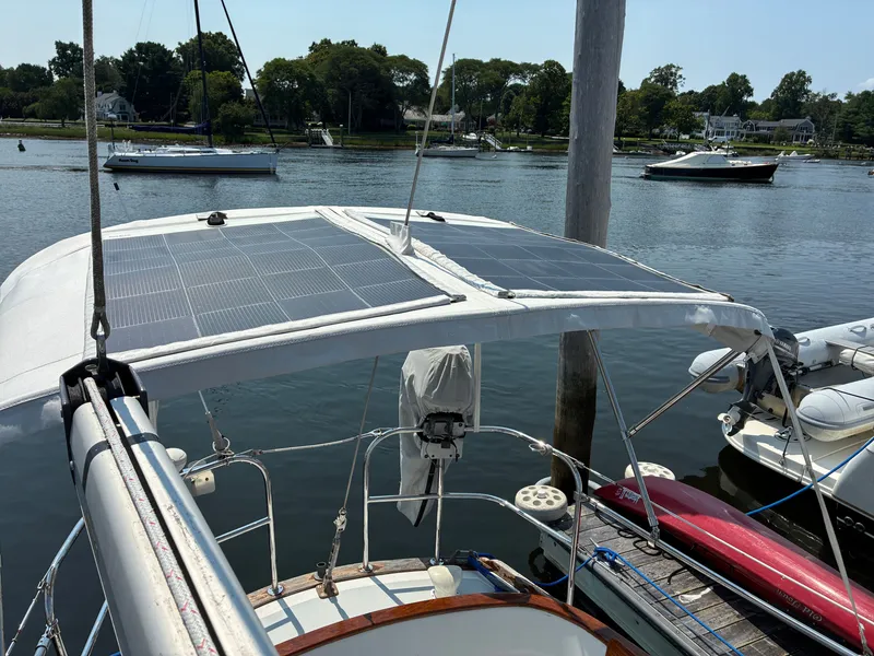 Slide: The Image of The image shows a sailboat with solar panels on the canopy, docked in a calm marina. - 26