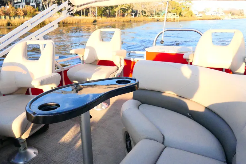 Slide: The Image of 2021 Avalon VENTURE 1875 pontoon boat interior with seating and table on a sunny day. - 23