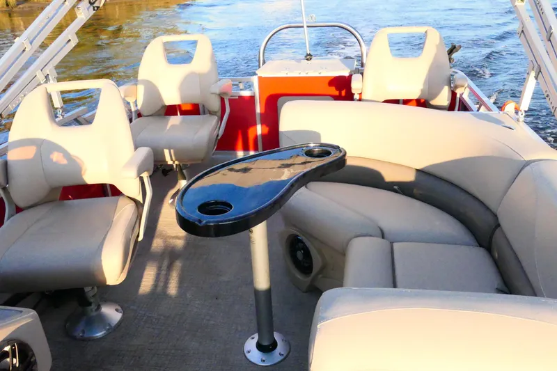 Slide: The Image of 2021 Avalon VENTURE 1875 boat interior with beige seating and a black table on water. - 7