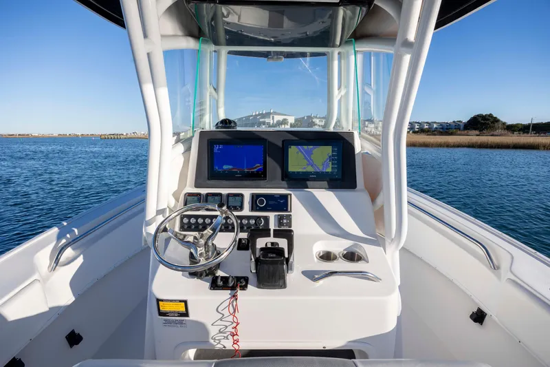 Slide: The Image of 2014 Cape Horn 27 XS boat cockpit with navigation screens and steering wheel on open water. - 17