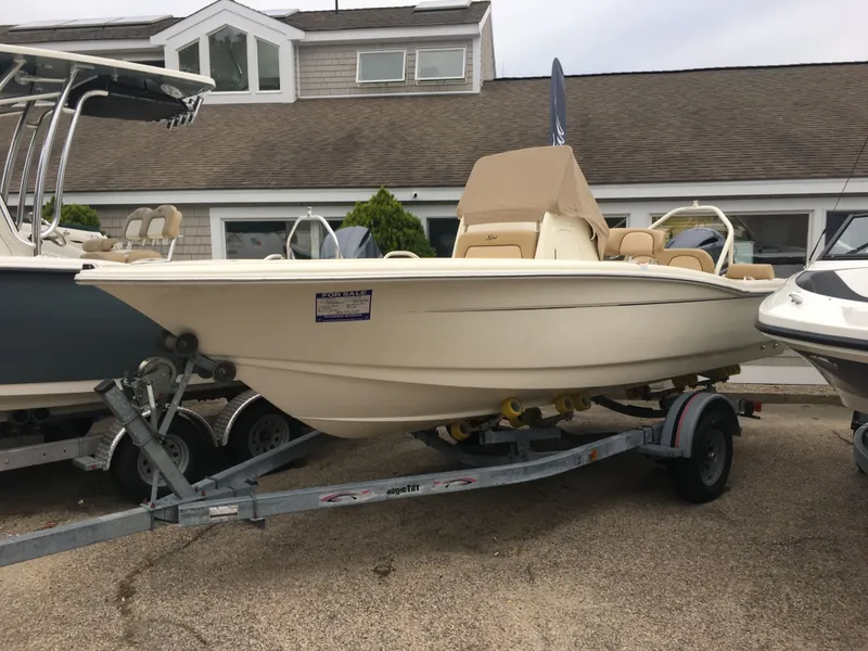 The Image of 2017 Scout 195 Sportfish boat on trailer in front of building. - 0