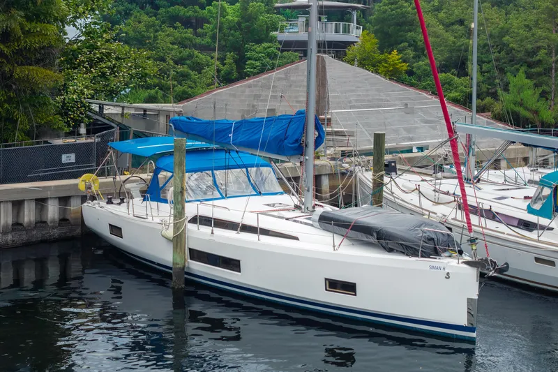 The Image of 2020 Beneteau Oceanis 46.1 sailboat docked in a marina, surrounded by lush greenery. - 0