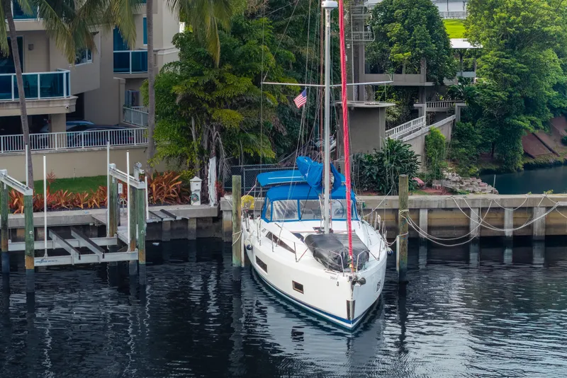 Slide: The Image of 2020 Beneteau Oceanis 46.1 yacht docked by waterfront homes, surrounded by lush greenery. - 5