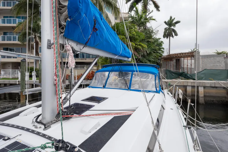 Slide: The Image of 2020 Beneteau Oceanis 46.1 sailboat docked, featuring blue sail cover and lush surroundings. - 8