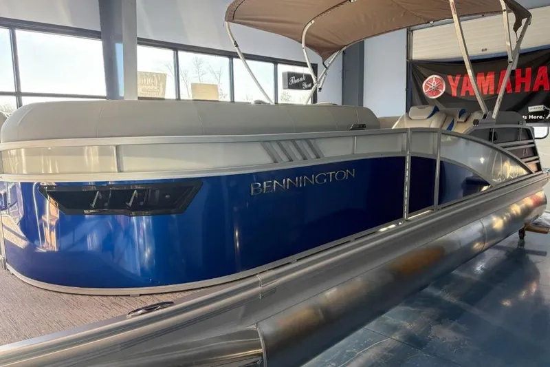 The Image of 2026 Bennington 23LXSFB pontoon boat with blue exterior and canopy in showroom. - 1