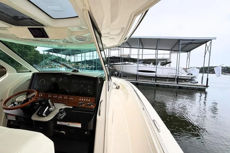 Slide: The Image of 2025 Tiara Yachts 38 LS helm view, docked at marina with covered slips. - 12