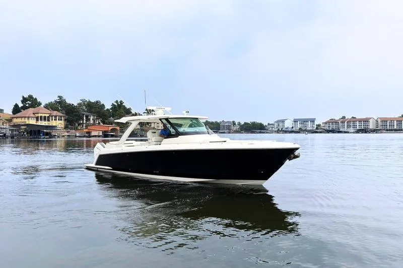 Slide: The Image of 2025 Tiara Yachts 38 LS cruising on a calm lake near waterfront homes. - 17