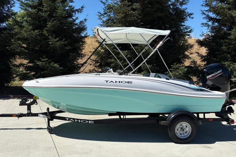Slide: The Image of 2026 Tahoe T16 boat with canopy on trailer, parked outdoors. - 3