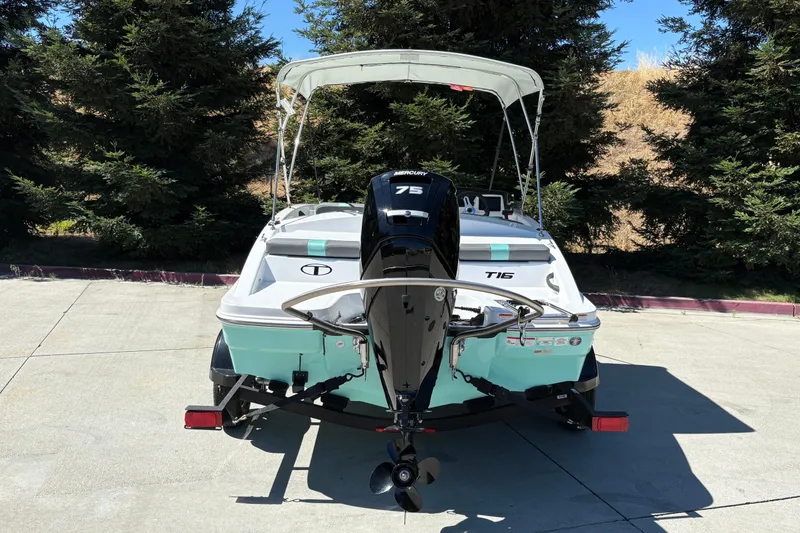 Slide: The Image of 2026 Tahoe T16 boat with outboard motor, parked on concrete, surrounded by trees. - 10