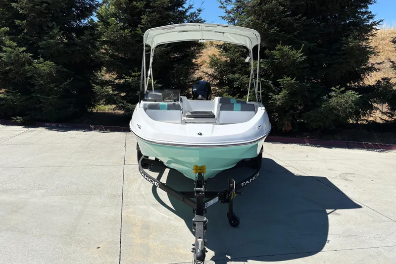 Slide: The Image of 2026 Tahoe T16 boat on trailer, parked outdoors with trees in background. - 7