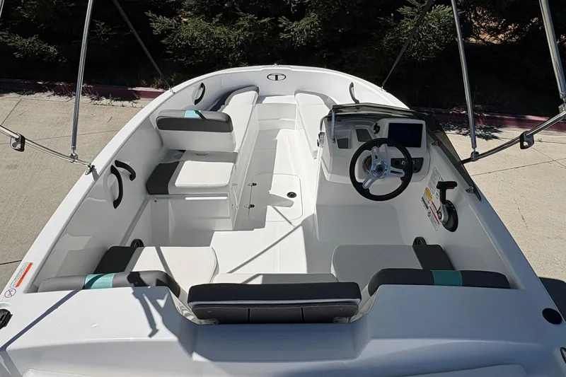 Slide: The Image of 2026 Tahoe T16 boat interior with seating and steering console, docked outdoors. - 16