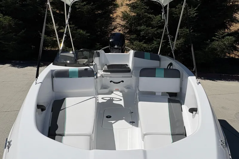 Slide: The Image of 2026 Tahoe T16 boat interior with seating and canopy, parked outdoors. - 15