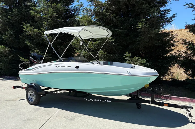 Slide: The Image of 2026 Tahoe T16 boat with canopy on trailer, parked outdoors. - 2