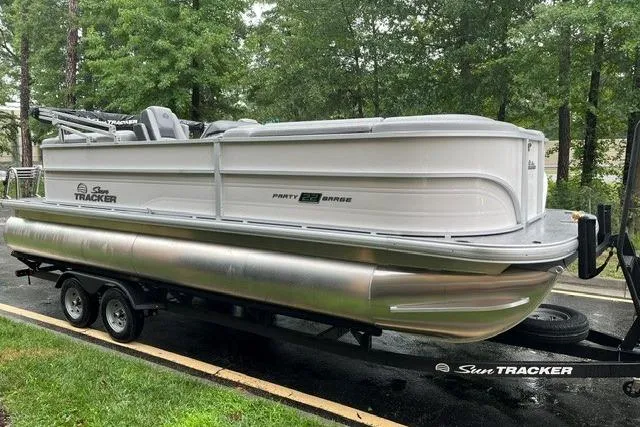 Slide: The Image of 2026 Sun Tracker Party Barge 22 DLX pontoon boat on trailer, parked outdoors. - 1