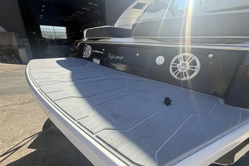 Slide: The Image of 2023 Regal LS4 Surf boat with sunlit deck and speakers in a marina setting. - 20